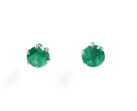 A pair of white gold single stone emerald stud earrings, a circular mixed cut emerald, claw set to threaded posts and screw f