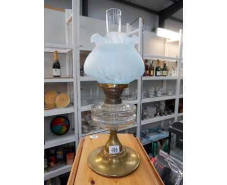 An oil lamp with brass base, glass font and glass shade