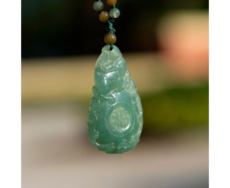 A beautiful hand carved jade pendant depicting two rabbits resting atop of a sphere, and a carving of a bat just below the sp