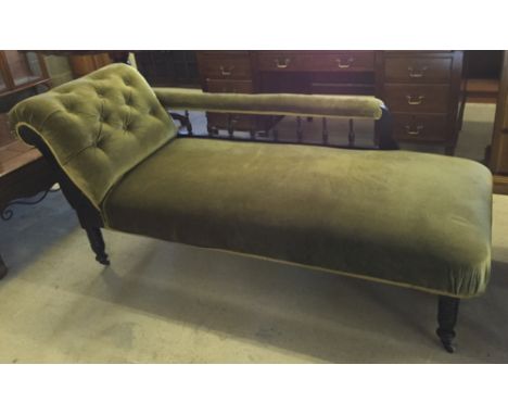 A Victorian chaise longue with turned legs, ceramic casters, spindle rail and green velvet upholstery.