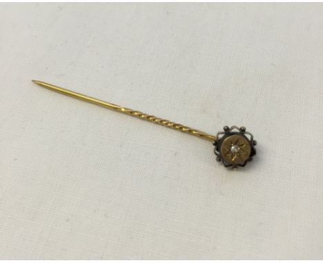 A Victorian 13K gold stick pin set with a single diamond.