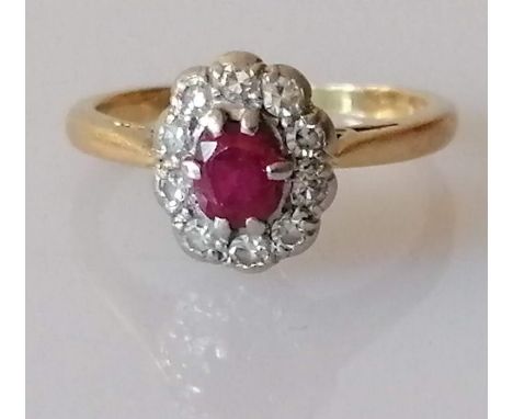 An ruby and diamond cluster ring on a yellow gold setting, the oval pinkish ruby, 5mm x 3mm, surrounded by ten round brillian