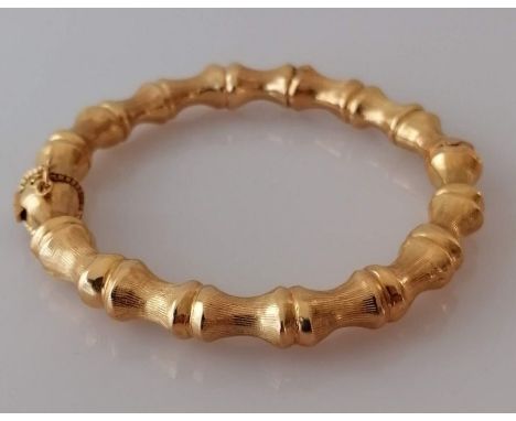 A yellow gold bangle in the form of bamboo with push clasp and safety chain, internal diameter, 55mm, unmarked, but testing f