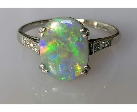 An Art Deco pinfire opal ring in a platinum and white gold claw setting flanked by single-cut diamonds to each shoulder, the 