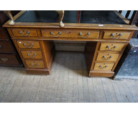 An early 20th Century light oak flat topped knee hole desk, having an assortment of nine drawers.