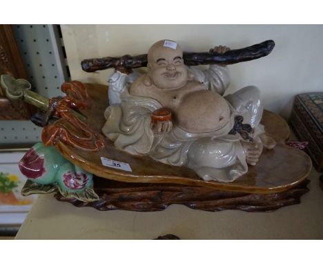 A contemporary Chinese ceramic model of a Buddha holding fruit.