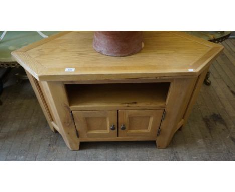 A modern light oak finished TV stand, having two panelled cupboard doors.