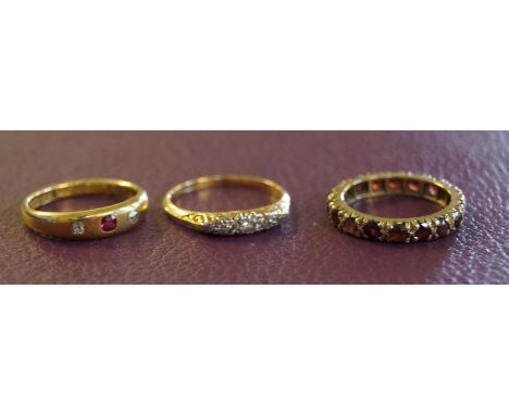 A 9ct yellow gold garnet full hoop ring, an 18ct yellow gold diamond ruby three stone ring, and an early 20th Century 18ct ye