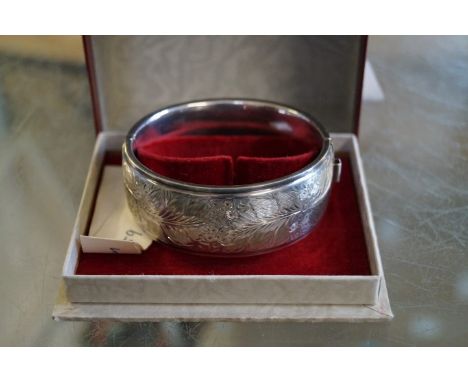 A Birmingham hallmarked silver hinged bangle, with foliate engraved decoration, maker H B & S, cased.