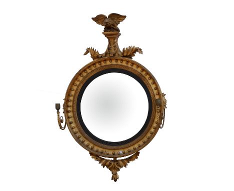 William IV giltwood and gesso convex mirror, with a spread eagle cresting above scrolling leaves, the frame applied with sphe