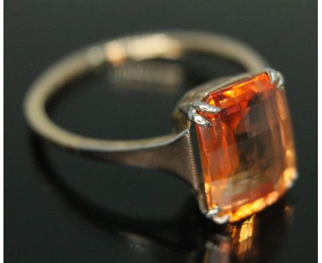 A fancy orange synthetic sapphire ring, the briollete cushion cut stone weighing approx. 4.01 carats, band marked '9ct', gros