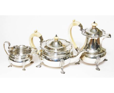 A George VI three piece silver tea set, the tea and coffee pots with ivory handles and finials, each piece raised on pad feet