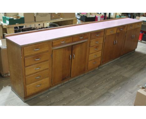 A pair of 1950s light oak kitchen units, patterned melamine tops, one with pull out slide and central cupboard flanked by dra