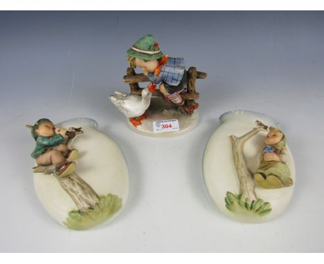 Two Hummel wall pockets together with a figurine