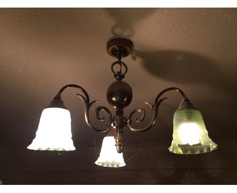 A pendant brass three-branch ceiling light with achromatizing green glass shades 