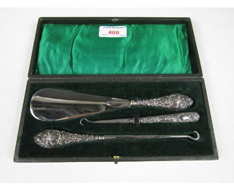 A cased George V silver handled button hooks and shoe horn set 