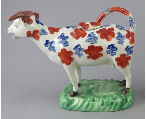 An early nineteenth century pearlware Swansea cow creamer, c.1820. decorated with red and blue enamel decoration and stands o