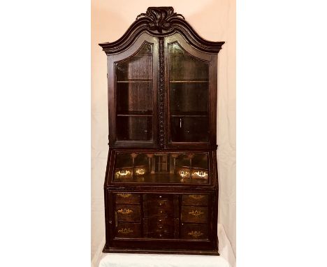 An early 18th Century walnut apprentice glazed bookcase on bureau, arch shaped cornice with a foliate carved centre, above a 