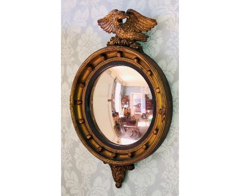 A Regency Irish guiltwood circular mirror, carving of an eagle finial, above a circular moulded frame, with beading around th