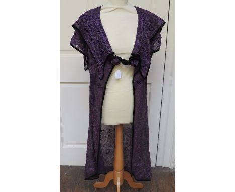 An Aubergine/Purple robe which would have been worn over another garment. The robe is heavily decorated in a braided design i