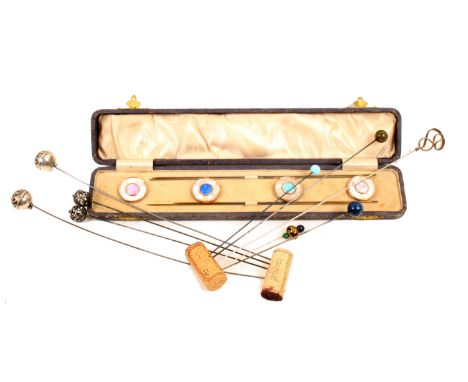 A collection of hat pins comprising a cased set wilt four pins and four mother of pearl and enamel circular mounts, a pair of