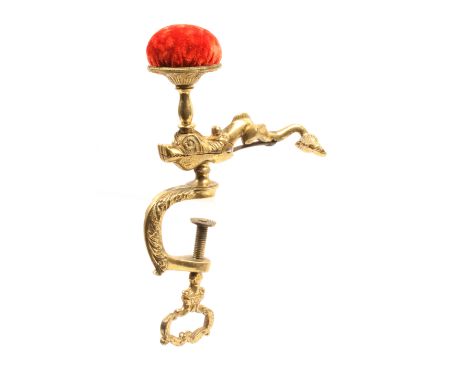 A good mid 19th Century cast brass sewing clamp modelled as a dolphin below a pin cushion, the decorated ‘c’ form frame with 