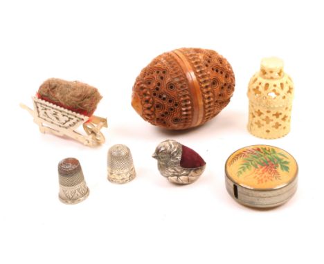 A mixed lot sewing comprising a pierced bone wheelbarrow pin cushion, 5.2cm, a Fern ware circular tape measure lacking tape, 