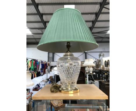 A large cut glass table lamp with brass fittings and green shade