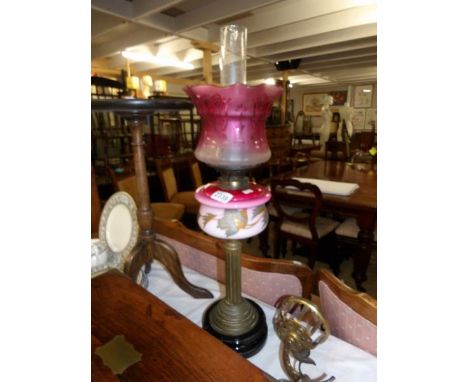 A Victorian oil lamp on pot base with reeded column, hand painted glass font and etched cranberry glass shade.