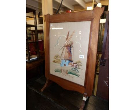 A tapestry of a windmill mounted in a mahogany fire screen.