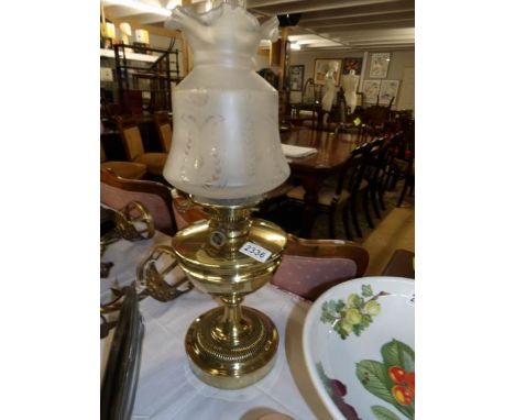 A brass oil lamp with etched shade.