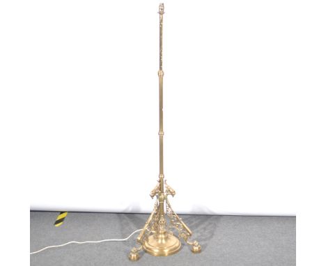 A brass standard lamp, converted to electricity, adjustable column, scrolled tripod base with mask heads, as assembled, 170cm