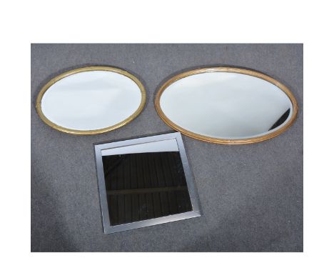 A gilt painted oval wall mirror, bevelled plate, reeded outlines 51cm x 80cm; similar mirror of smaller size; and a contempor