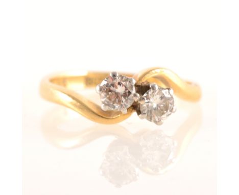 A diamond two stone crossover ring, the brilliant cut stones claw set in a yellow and white metal crossover mount marked 18ct