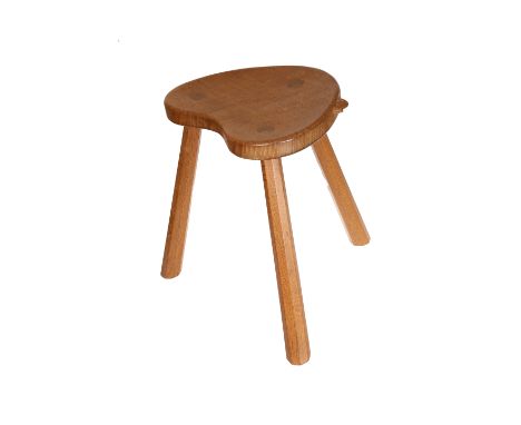 Robert Thompson of Kilburn, a Mouseman oak cow stool, early 1960's, the reniform adzed seat raised on three faceted splayed l