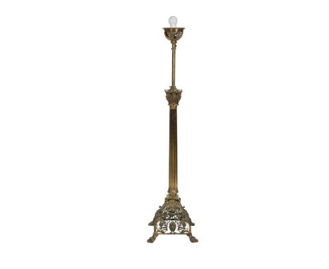 A late Victorian brass standard lamp, the Corinthian column stem issuing from a domed base embossed with masks, scrolls and f