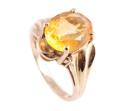 A citrine and gold ring, the oval cut citrine four claw set in an open heavily moulded twist design mount between tapering mo