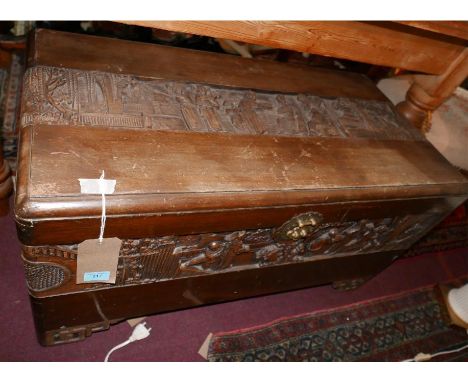 An early 20th century Chinese camphor wood trunk, carved with panels of figures in courtyard and garden scenes, bears plaque 