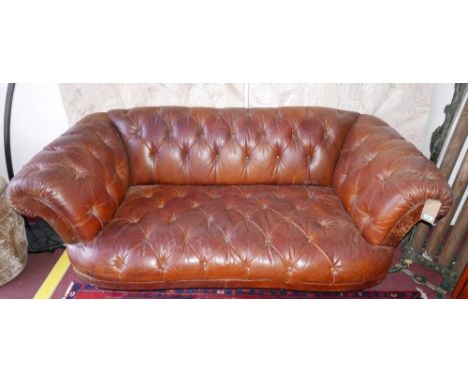 A Chesterfield style two seat sofa, with brown leather button back upholstery, raised on reeded baluster mahogany feet 