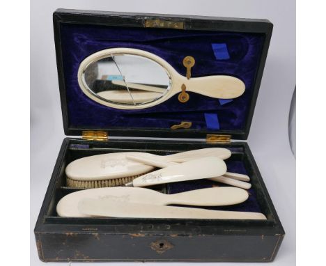 A late 19th century ivory vanity set, to include a mirror (glass cracked), a shoe horn with button hook, glove spreaders, two