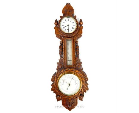 An early 20th century carved oak barometer, the enamelled dial of the clock decorated with Roman Numerals, the frame carved w