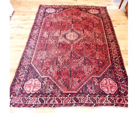 A Persian Qashqai carpet, the central medallion on a red field with blue spandrels, guarded by one frieze and two running bor