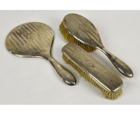WILLIAM NEALE LTD; a George V hallmarked silver backed engine turned three piece dressing table set comprising a circular han