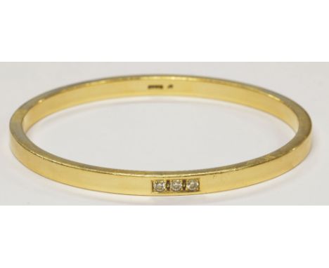 A 9ct yellow gold bangle set with three small diamonds, internal diameter 7.2cm, approx 44.4g.