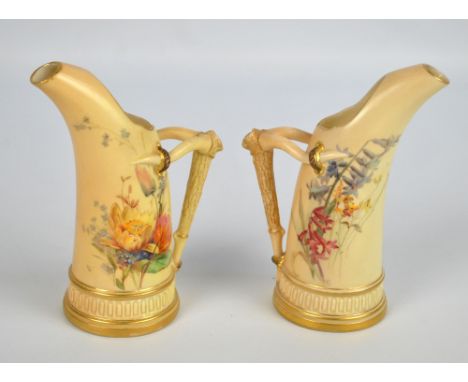 A pair of Royal Worcester blush ivory gilt heightened floral decorated porcelain tusk shaped ewers with branch effect handles