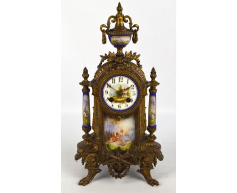 A late 19/early 20th century French gilt metal and porcelain eight day mantel clock surmounted with an urn above hand painted