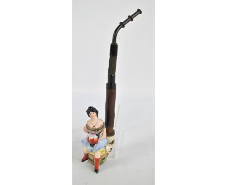 An early 20th century German porcelain, wood and bakelite pipe modelled as a seated Bavarian woman holding three mugs of beer