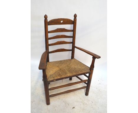 A 19th century ash and elm ladder back rush seated elbow chair.