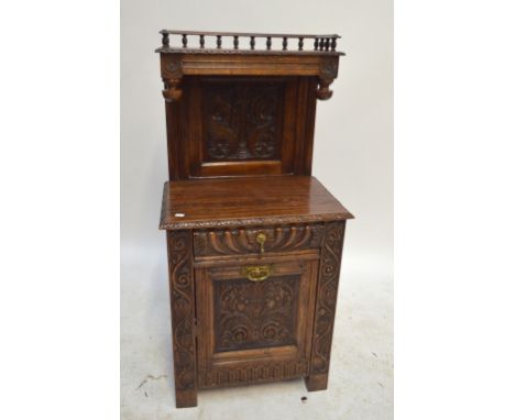 A late Victorian carved oak purdonium with upper shelf with bobbin gallery and side bosses carved panel back to shelf above s