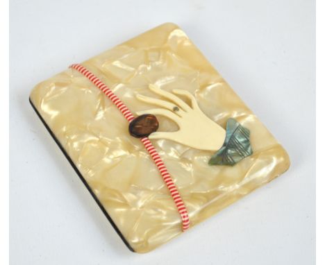 A mid-20th century celluloid cigarette case modelled as a purse with an applied hand opening the clasp, 9 x 8cm.
